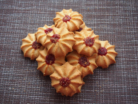 A few pieces of kurabye cookies lie on the brown tablecloth. Close up.