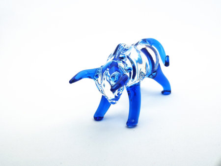 Glass figure of a bull with blue horns and legs on a white background. Close-upの写真素材