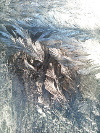 Shiny ice patterns on the frozen window pane. Texture.