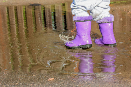 summer stroll kid in rubber boots in a puddle.の写真素材