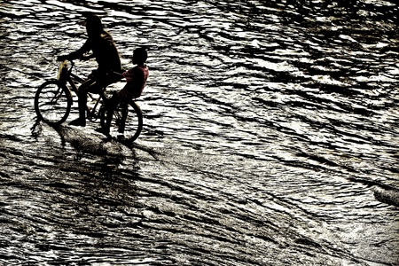 silhouette of brothers riding in floodの写真素材
