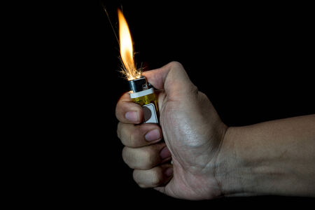 hand lighting up the lighter on black backgroundの写真素材