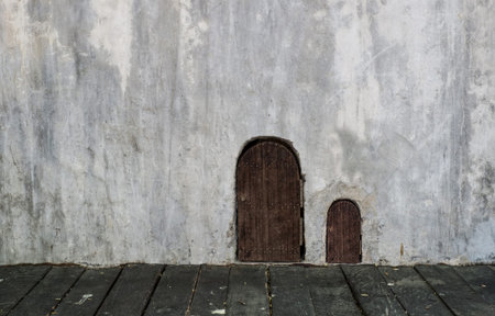 wooden small door and bigger door on concrete grungy wall with wooden floorの写真素材