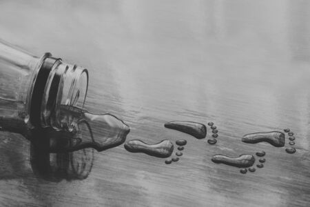 foot shaped drops of water walking away from bottle. conceptual image of dehydrateの写真素材