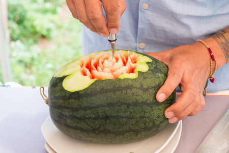 Fruit carving art, in preparation process with blurry artist in the backgroundの写真素材
