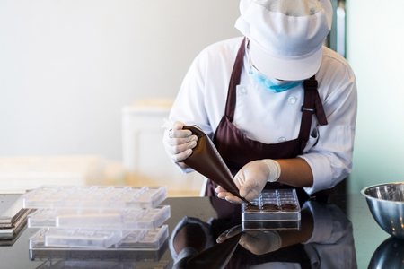 Kitchen staff preparing chocolate candies on marble table in the kitchenの写真素材