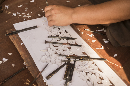 Thai style hand craft, artist carving beautifully on wood with draft paperの写真素材