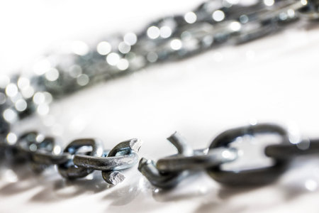 Broken chain on white surface, selective focus shallow depth of field
