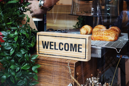 Wooden welcome sign in bakery shop photograph through the window glassの写真素材