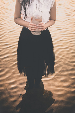 Llady holding a bottle of water standing in lakeの写真素材