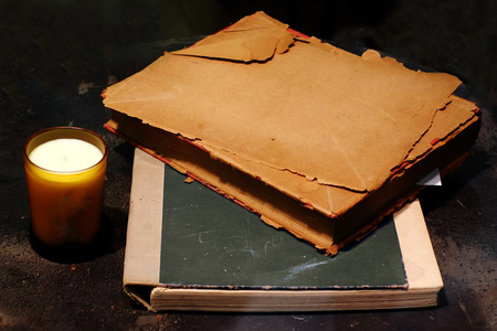Harsh dark lighting still life art of old papers on old book and a cup of candle lightの写真素材