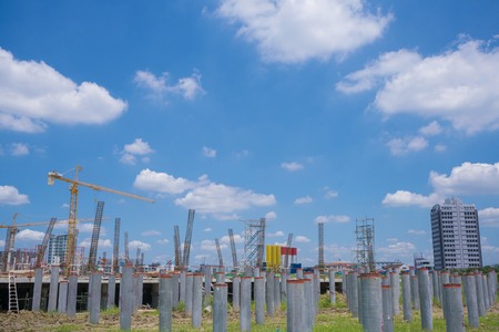 Crane operating in large construction site in sunny day. Water supply tubes are being installed into the ground and metal poles structure are preparedの写真素材