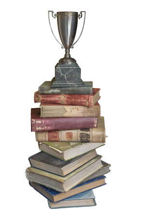 Stack of old vintage books with retro trophy on top isolated on white backgroundの写真素材