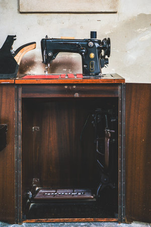 Old vintage pedal sewing machine with rustic grungy cement wall