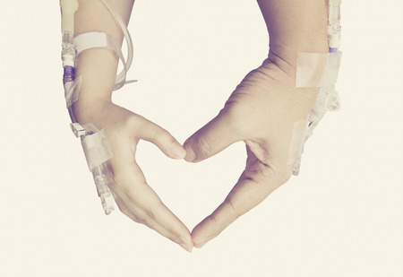 Patients' hands with sodium drip needles, two hands form a shaped of heart isolated on white backgroundの写真素材