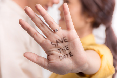 Hand wearing wedding ring with unidentified blurry couple in the backgroundの写真素材