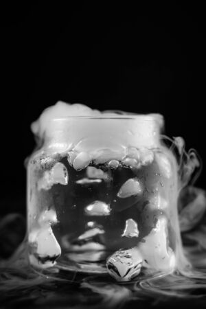 Dry ice cubes dropped into a glass jar starting to creat smokeの写真素材
