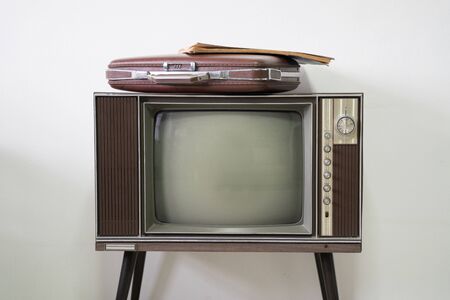 Old vintage briefcase on old television in white roomの写真素材