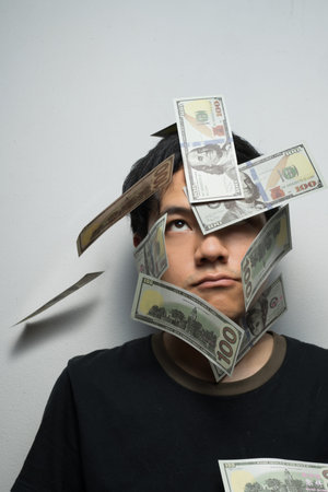 Fake money US bills falling on Asian man headの写真素材
