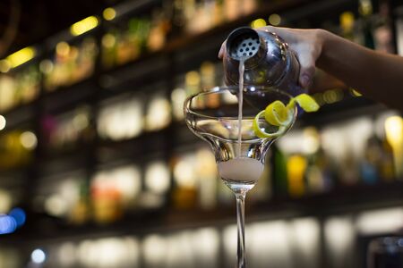 Bartender pouring coctail, selective focus with bokeh backgroundの写真素材