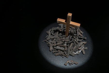 Wooden cross in the pile of guns with dark environment