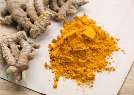Turmeric powder and turmeric on wooden backgroundの写真素材