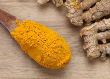 Turmeric powder and turmeric on wooden backgroundの写真素材