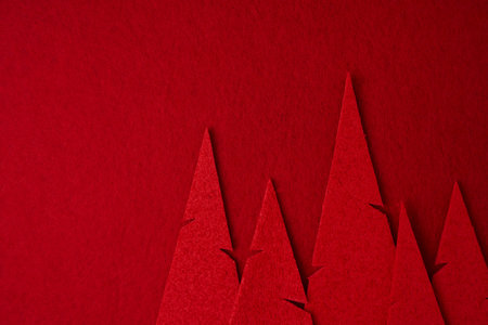 Creative Christmas tree shapes made of red textile on a bright red festive background. Simple Christmas or New Year concept with space for textの写真素材