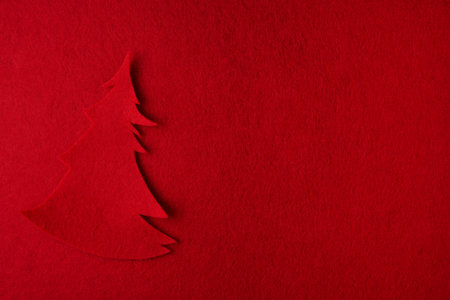 Creative shape of a fir tree made of red textile on a bright red background. Simple Christmas or New Year concept with space for textの写真素材