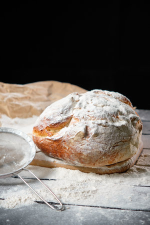 fresh loaf of sprinkle breadd with flour on a wooden background