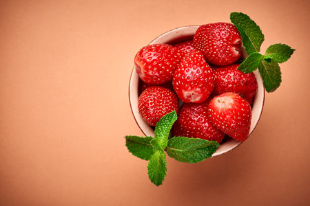 Strawberries in bowl on orange. Place for textの写真素材