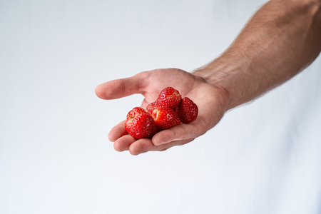 strawberries in a man's hand on a white background. Hand holding strawberry on whiteの写真素材
