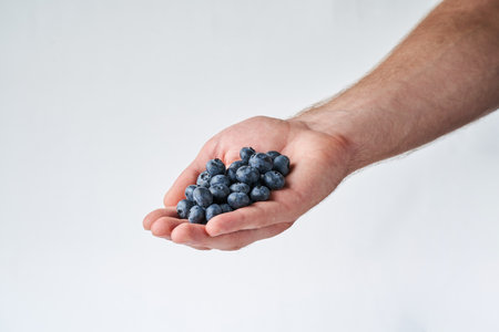 blueberry in hand on white. Male handの写真素材