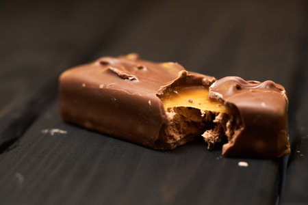 Appetizing broken chocolate bar with caramel and nuts on a darkの写真素材