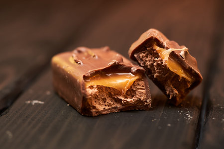 Appetizing broken chocolate bar with caramel and nuts on a darkの写真素材