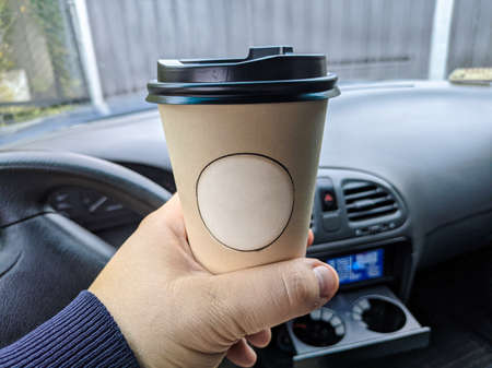 delicious aromatic coffee in the car. cup in the car. glass in hand. driver with coffee. glass with a drink on the trip. milkshake in the carの写真素材