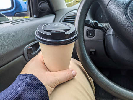 delicious aromatic coffee in the car. cup in the car. glass in hand. driver with coffee. glass with a drink on the trip. milkshake in the carの写真素材