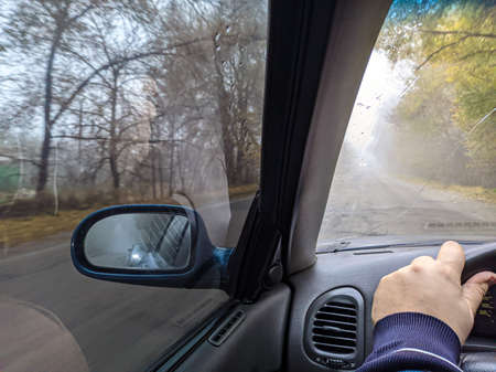 driver driving a car. driving on a bad road. crack on the glass. dangerous road. control of the car in the fog. fog and road. car on a wet road.の写真素材