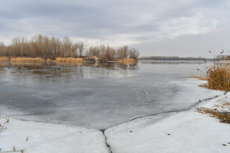 winter landscape with water. In front of a lake Panorama, mirror effect of the cloudy sky and the trees around it. Calm water and reflections from trees and sky. Pure Northern nature.の写真素材
