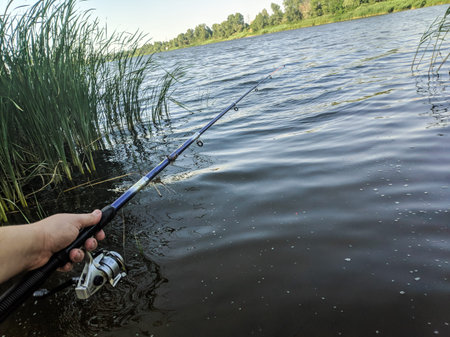 fishing on the river. fisherman with a fishing rod. catch . Fishing rod wheel closeup, man fishing...