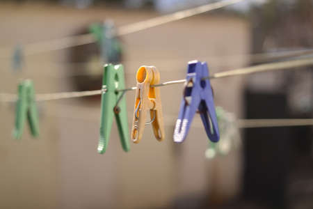 old pegs on a rope. One old retro clothespin wooden on a linen rope. Work on the house, washing, drying linen. Old Dirty Blue and Pink clothes peg on a rope Wire isolated on blurred backgroundの写真素材