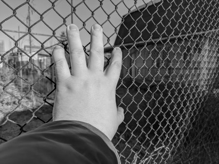 iron grate. steel mesh. the hand is holding the grace. a man's hand holds a steel mesh. conclusion. gate. fence. dream of freedom. jail. A Variety Of Prison Stories And Angles Available.の写真素材