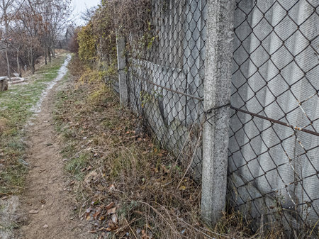 iron fence made of mesh. iron and concrete fence. man walking along an old fence.の写真素材