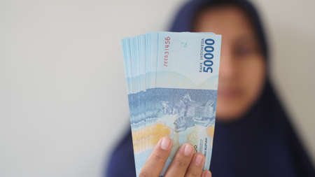 Yogyakarta, Indonesia - August 28, 2020: Indonesian rupiah currency, around 50,000 Indonesian money, is held by women's handsのeditorial素材