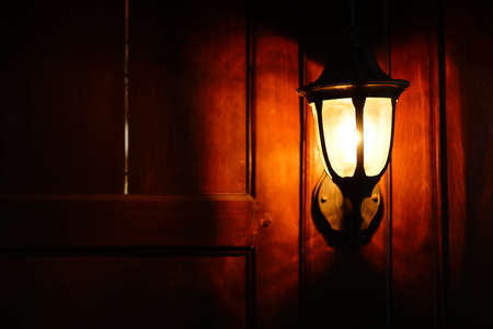 Classic lamp on wooden wall. The light is yellowの写真素材