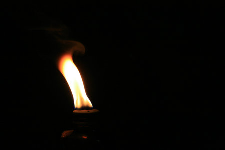 A fire burning in an oil lamp on a black background