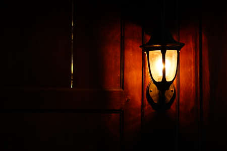 Classic lamp on wooden wall. The light is yellowの写真素材