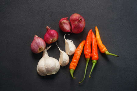 Some red chilies, shallots and garlic on a black backgroundの写真素材