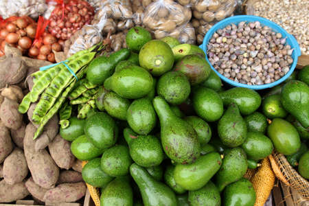Avocados, bitter bean, sweet potato, potato and onion at a traditional shop. Focus selection in avocadoの写真素材