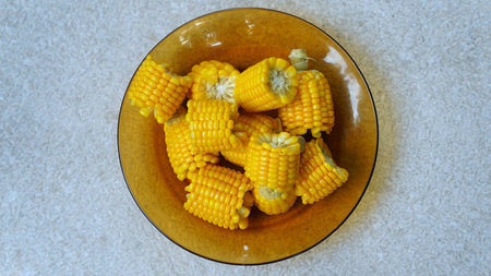 Pieces of boiled corn on a yellow glass plate. Focus selected